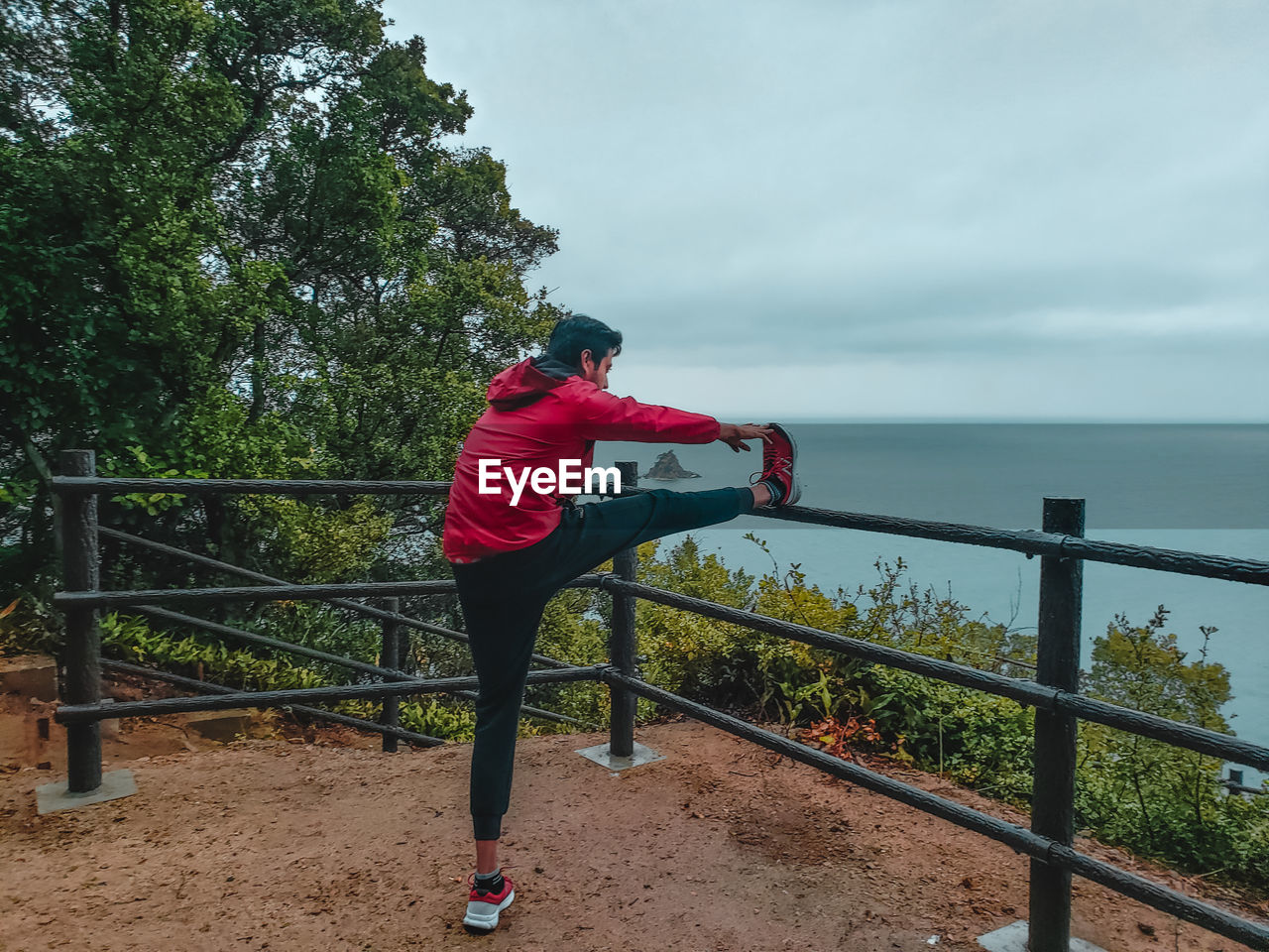 MAN STANDING ON RAILING AGAINST SEA