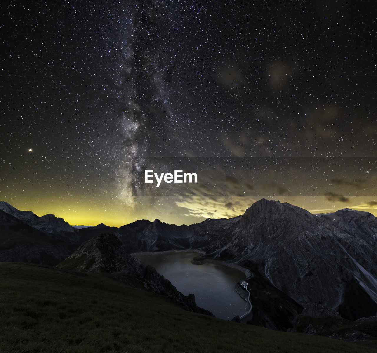 Scenic view of lake by mountains against sky during sunset