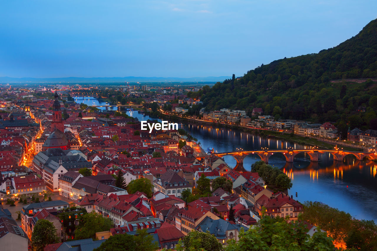 HIGH ANGLE VIEW OF RIVER BY ILLUMINATED BUILDINGS AGAINST SKY