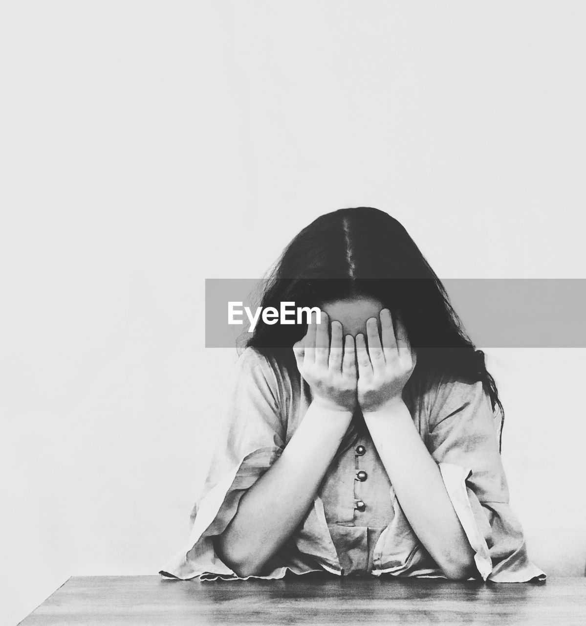 Worried girl covering face against white background