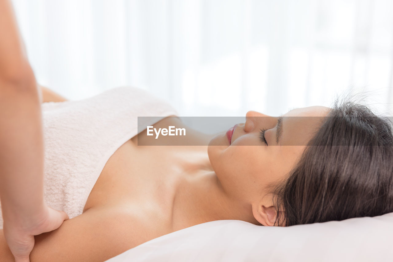 In a spa salon, a young woman enjoys massage therapy.