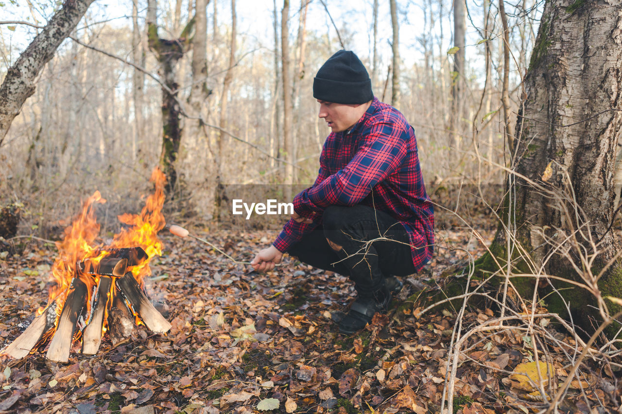 Man roasting food in campfire at forest