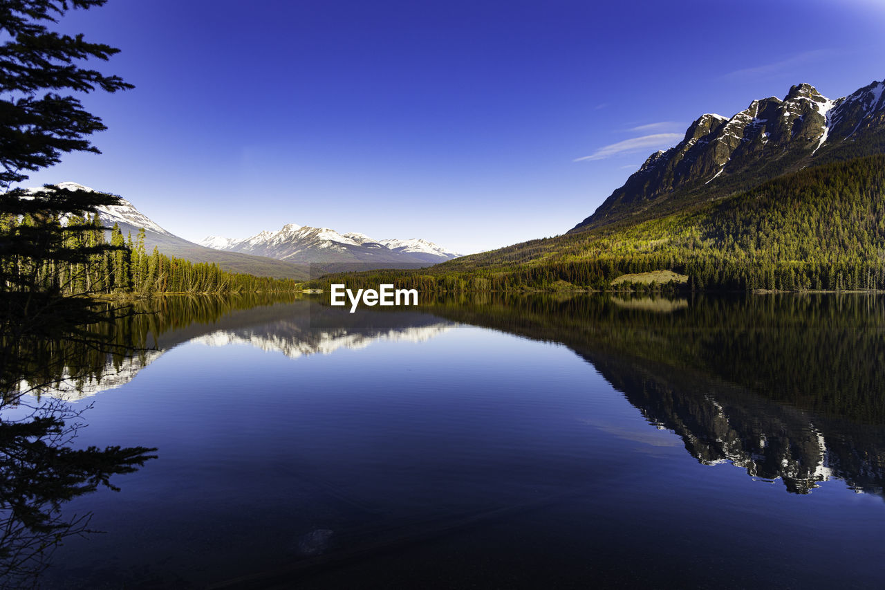 Scenic view of lake and mountains against clear blue sky