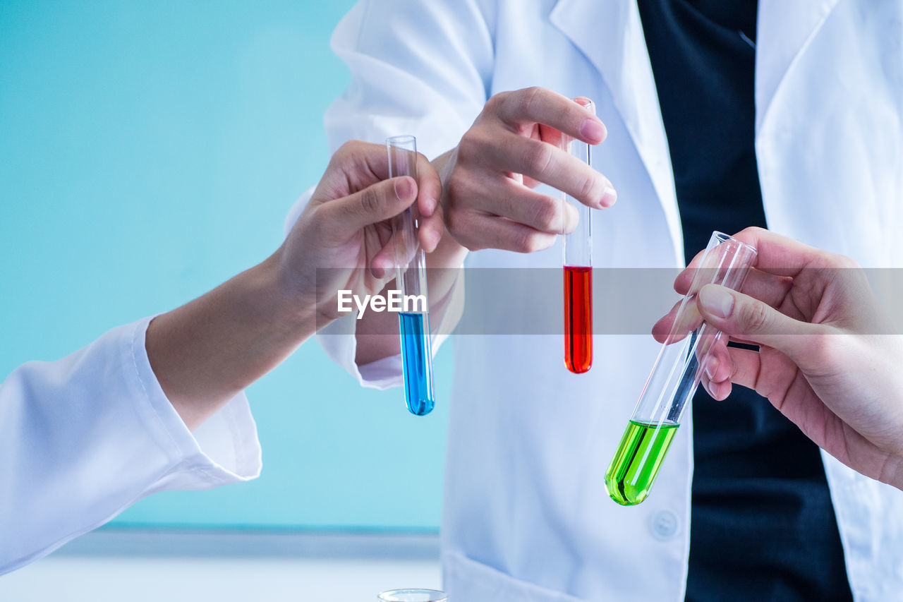 Cropped image of scientists holding test tubes