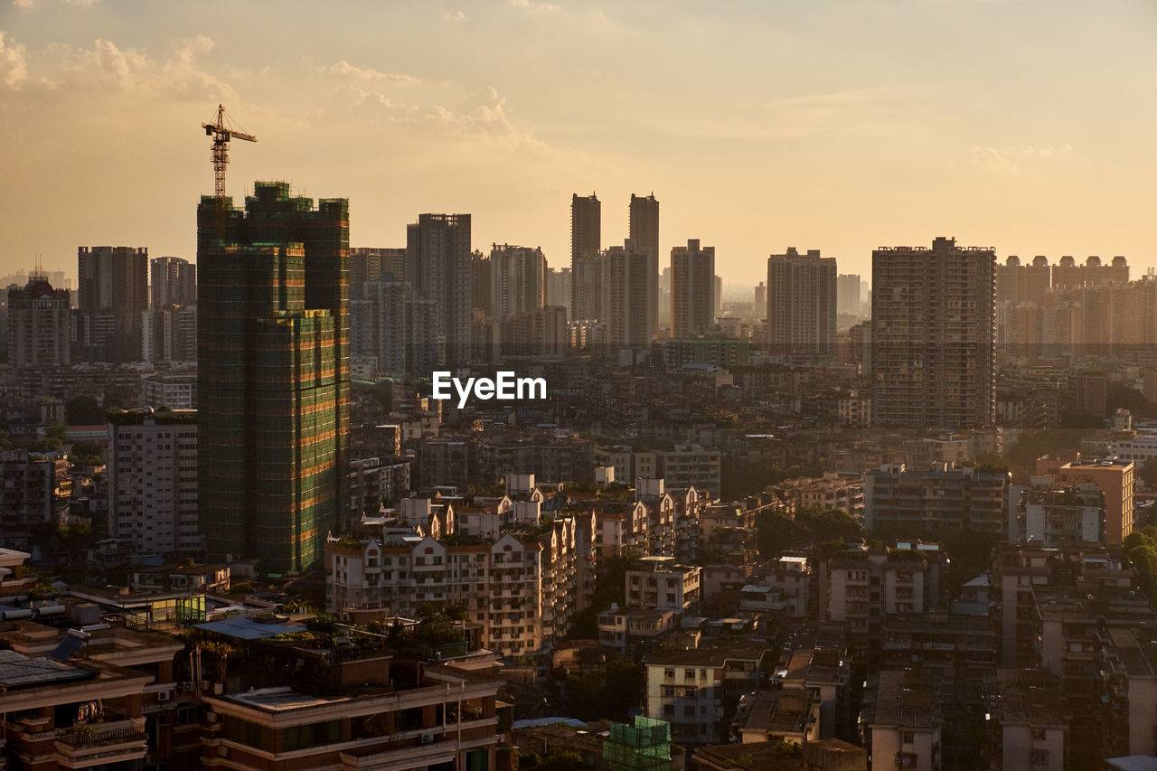 Aerial view of buildings in city against sky during sunset