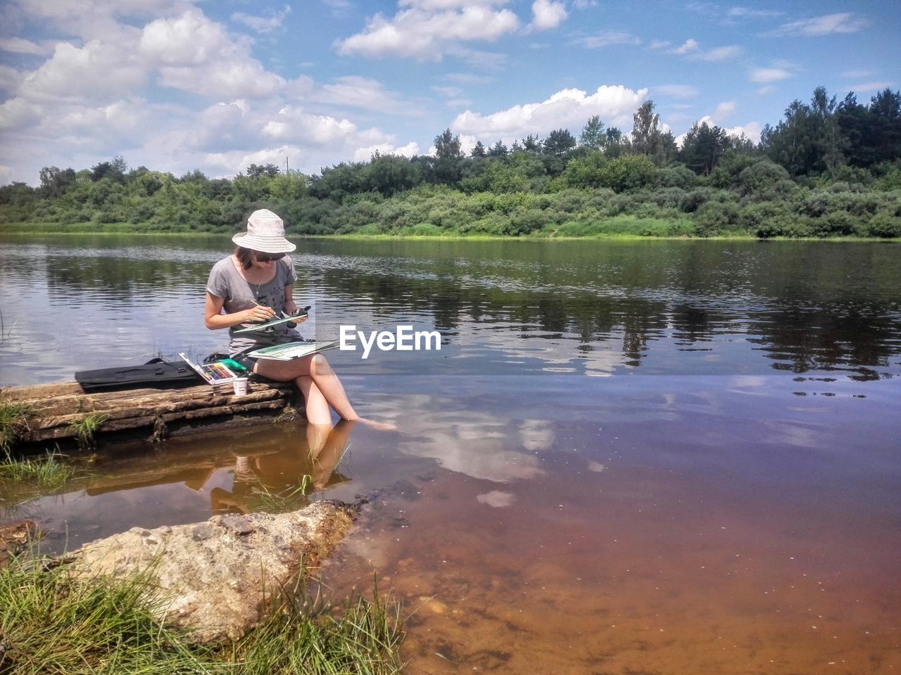 Man sitting in lake against sky