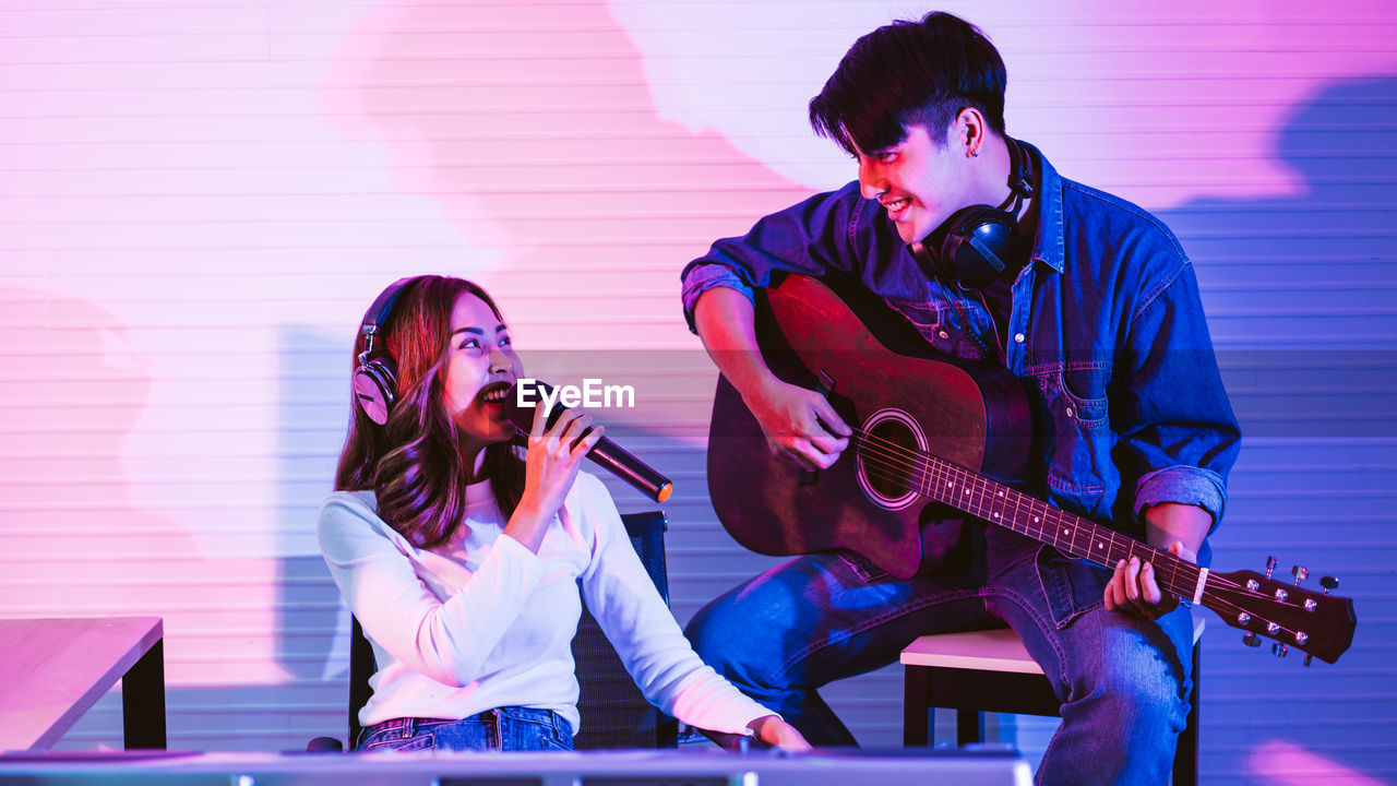 YOUNG MAN PLAYING GUITAR AT MUSIC CONCERT