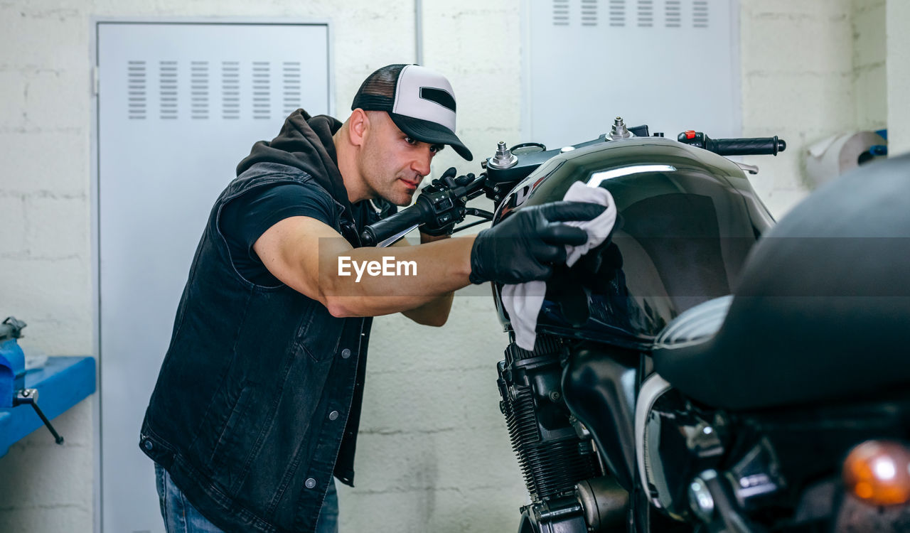 Man cleaning motorcycle in garage