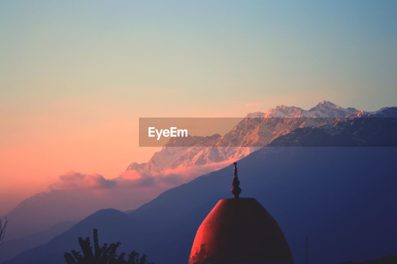 Dome of a temple with the backdrop of the himalayan ranges at sunset