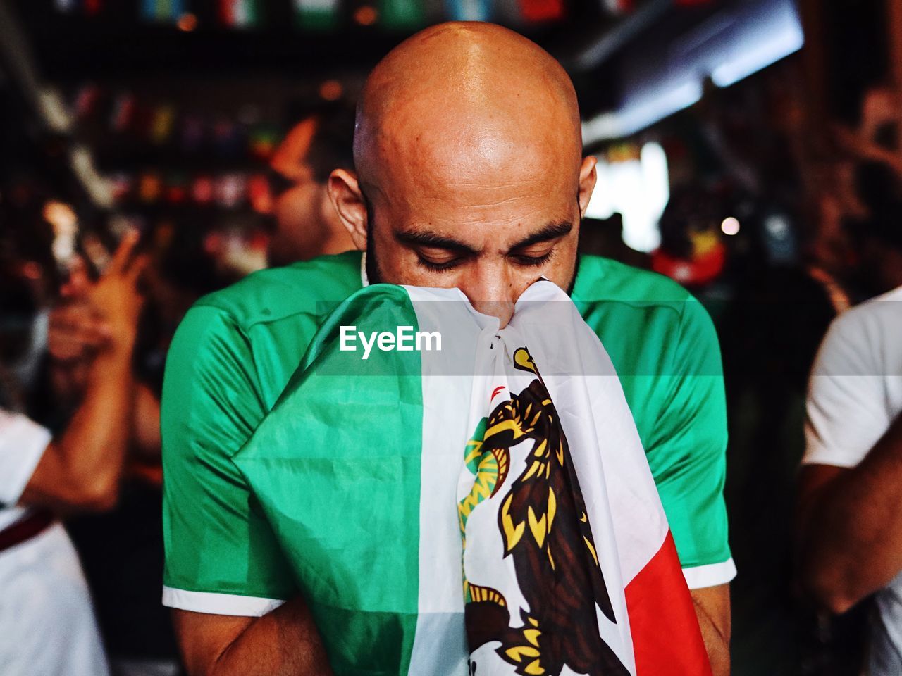 Bald man with eyes closed holding flag