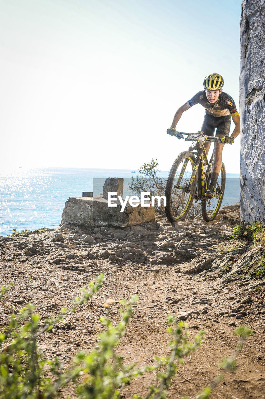 MAN RIDING BICYCLE ON SHORE