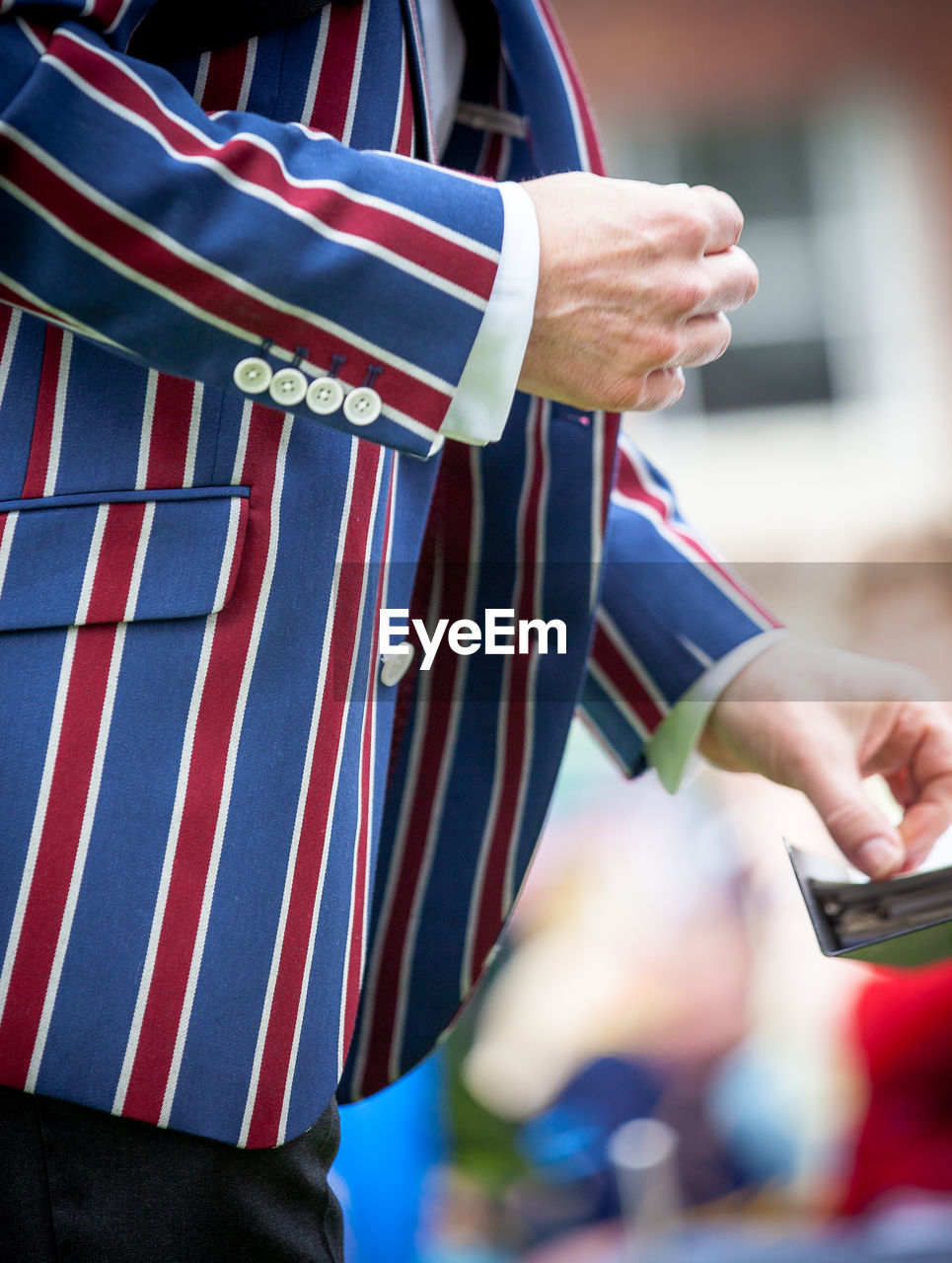 Midsection of man wearing striped blue and red jacket