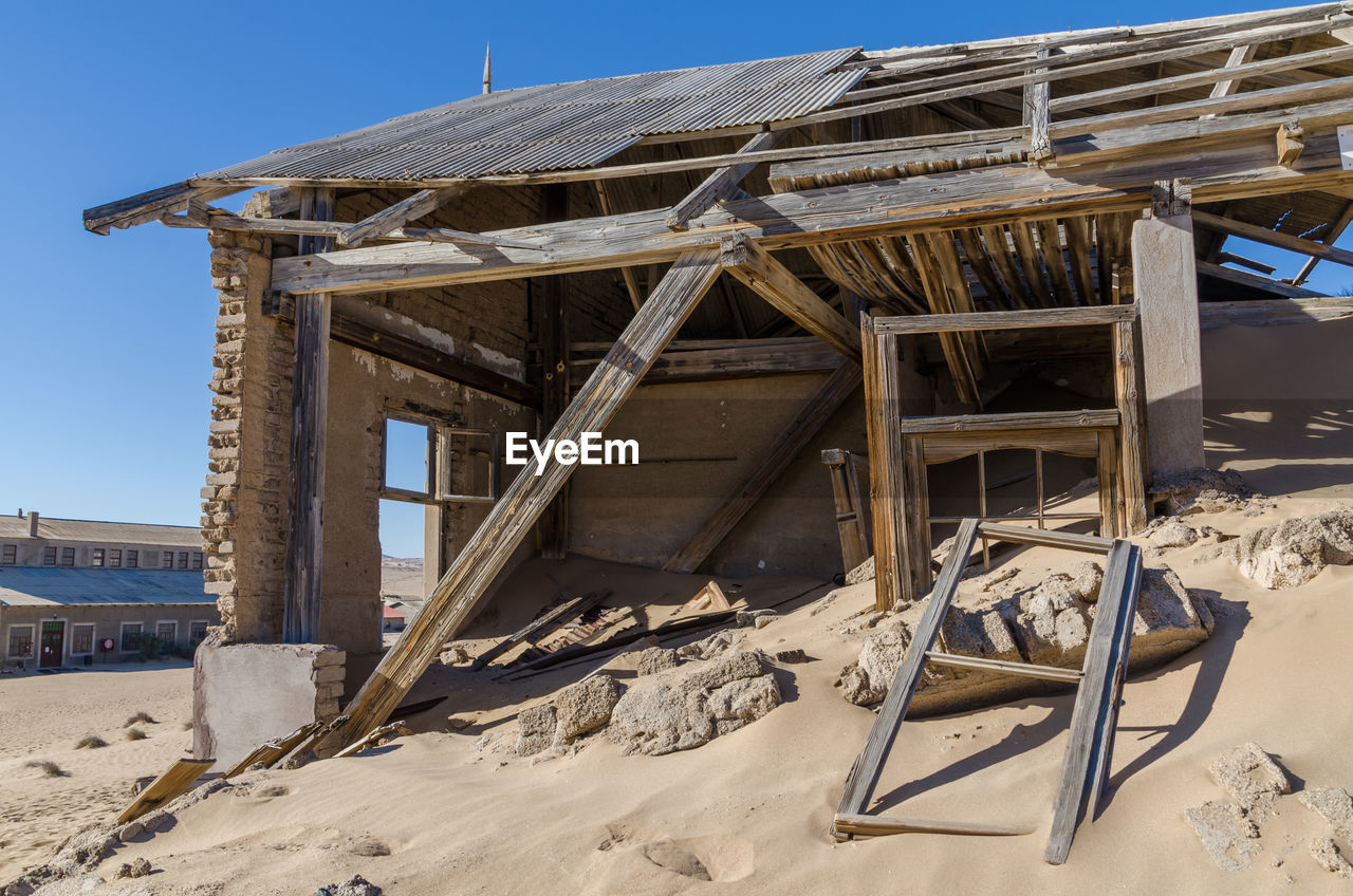 Abandoned buiding in desert against sky at ghost town kolmanskop, namibia