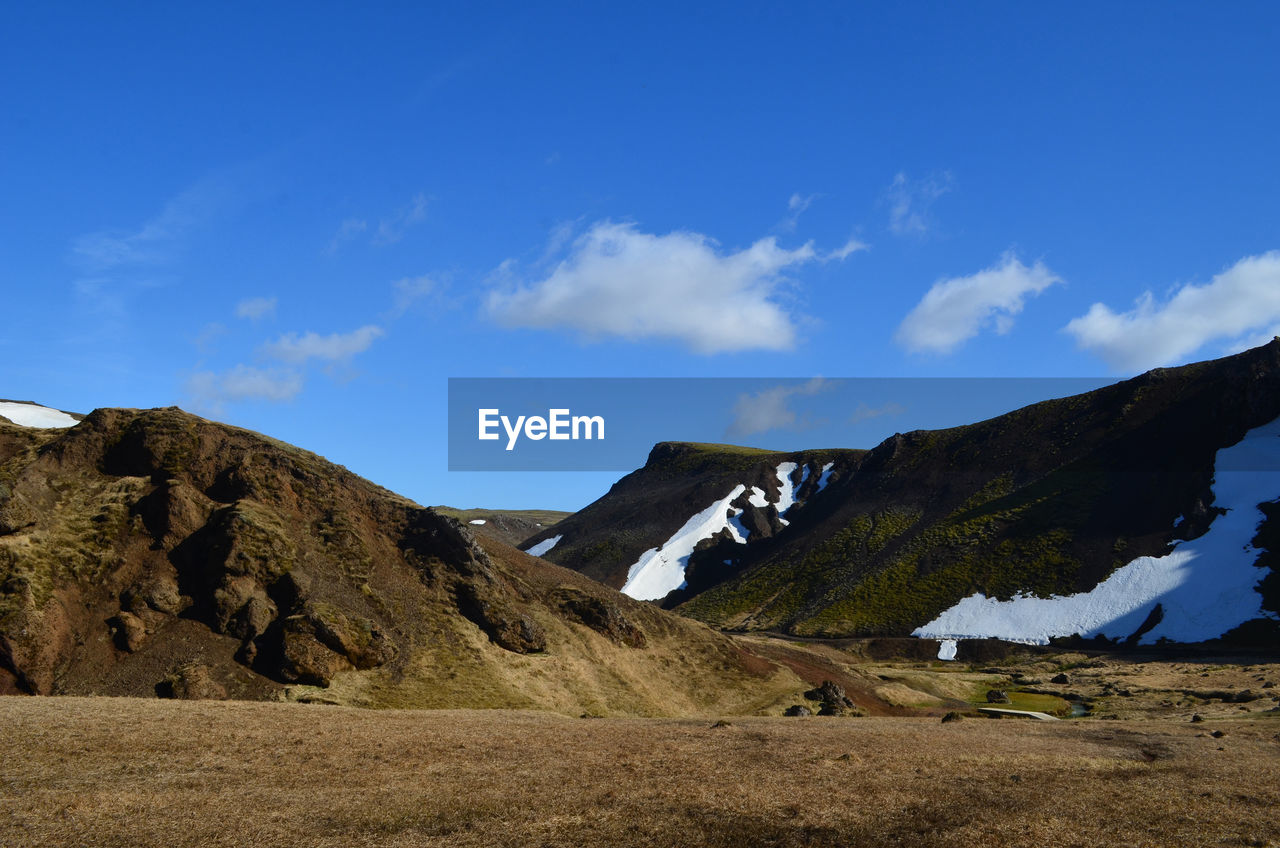 Spring thaw with snow patches on mountains surrounding a valley in remote iceland.