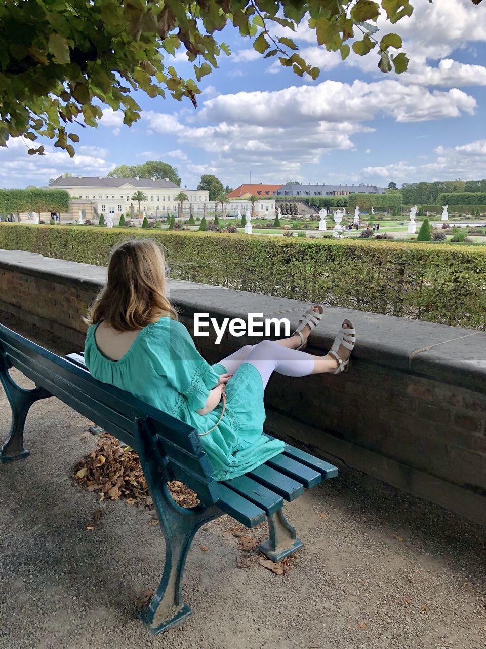 Girl sitting on bench against sky