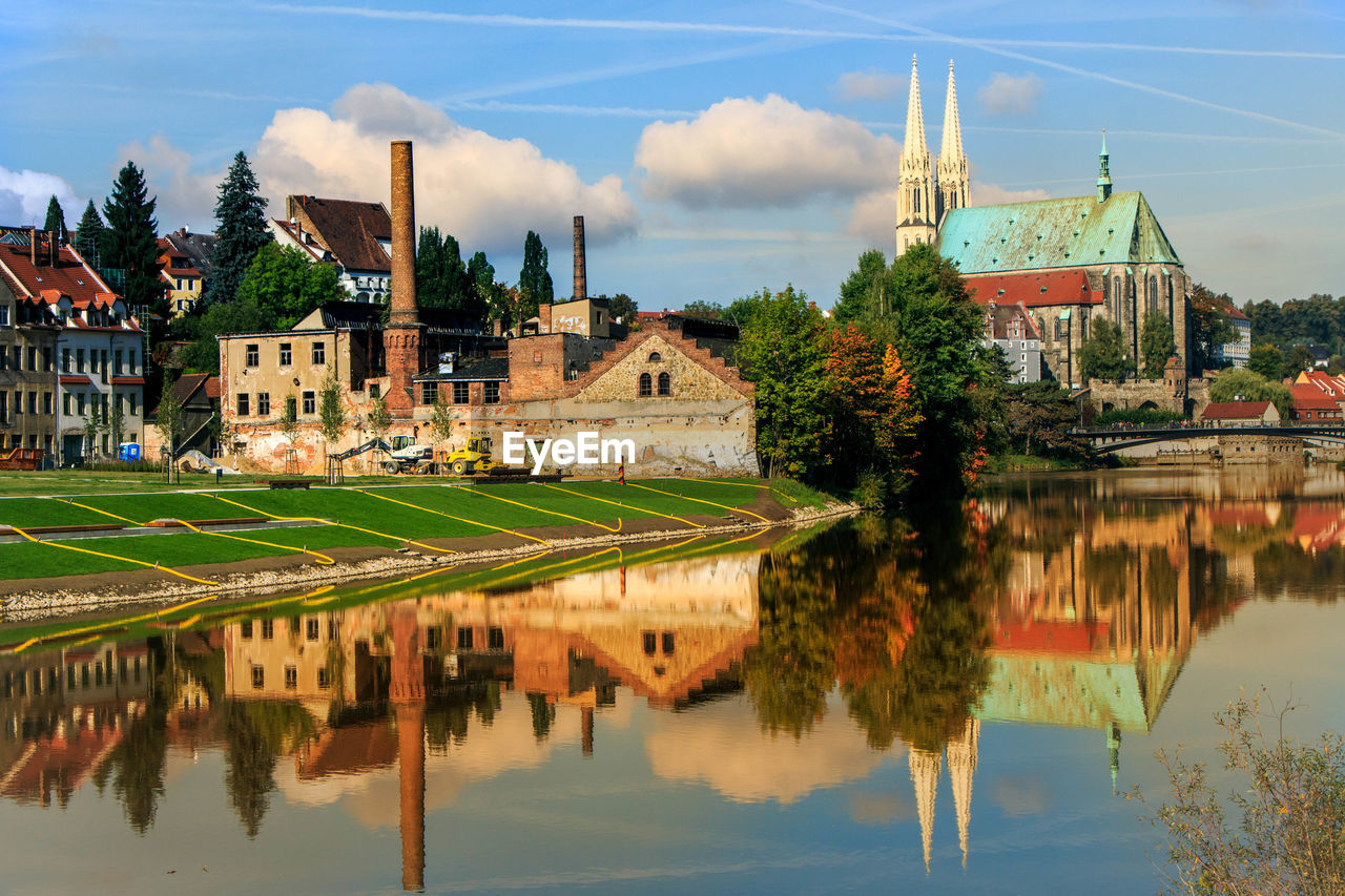 Scenic view of lake by buildings against sky in city