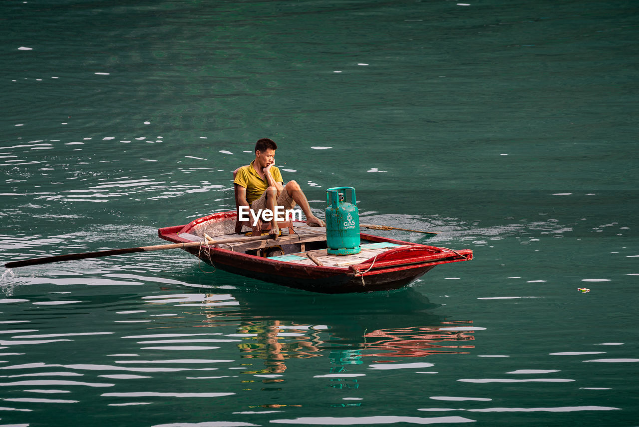 MAN SITTING IN BOAT AT LAKE