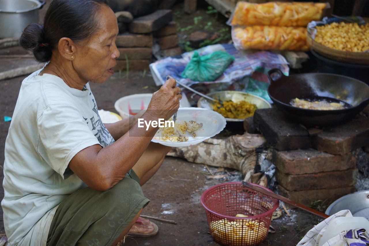 SIDE VIEW OF WOMAN HOLDING FOOD