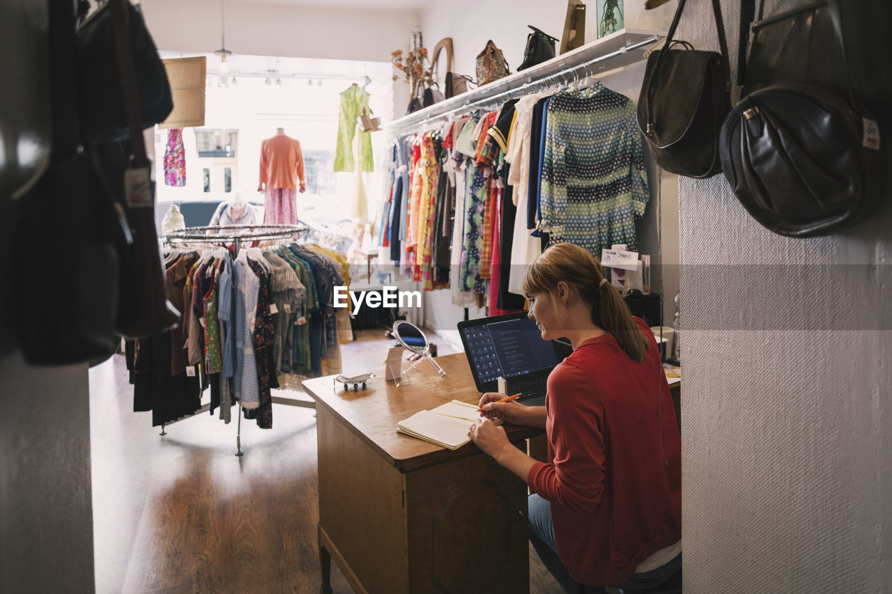 Woman working at desk while sitting in thrift store