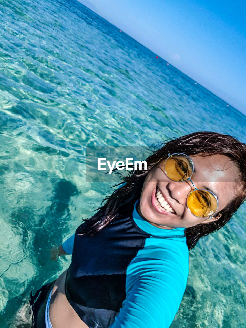 Portrait of smiling young woman wearing sunglasses in sea