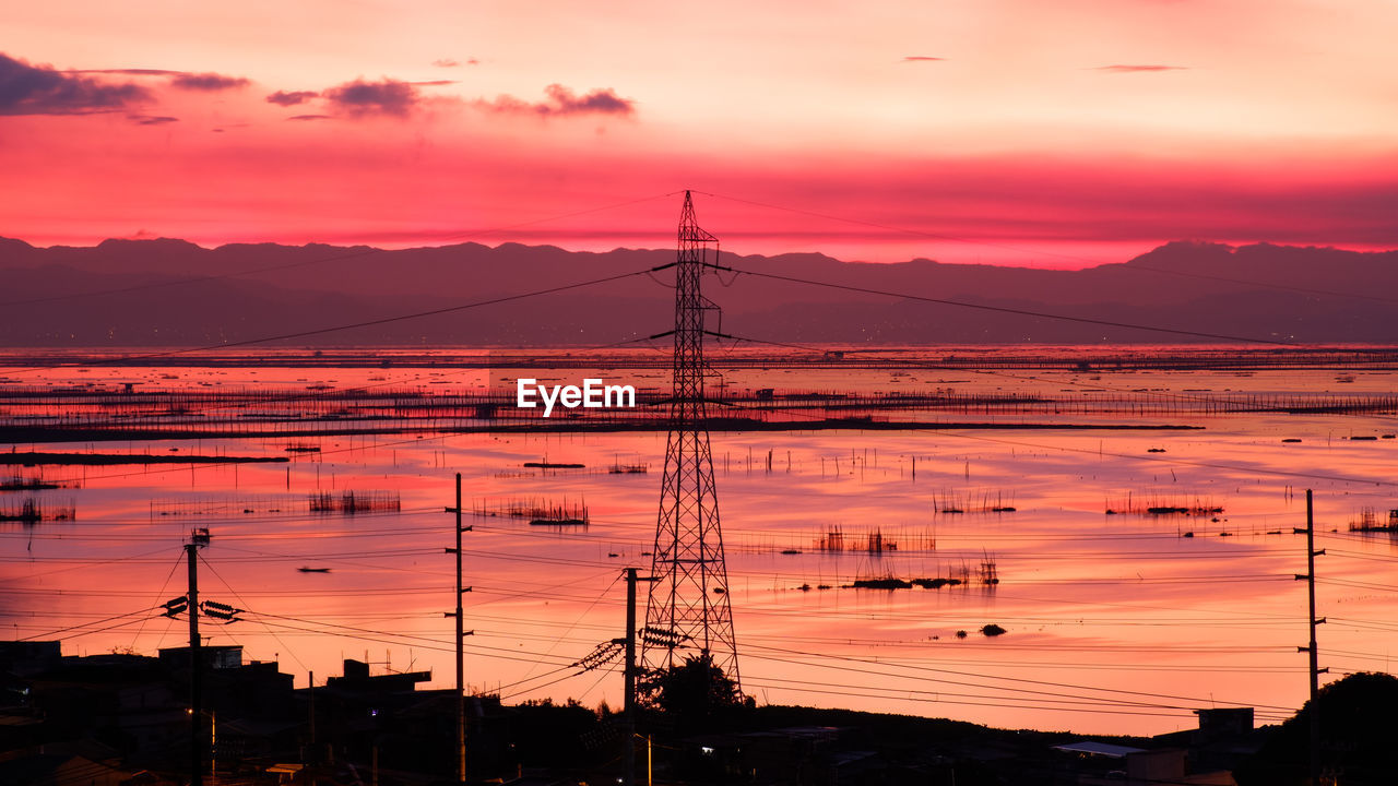 Silhouette electricity pylon against dramatic sky during sunrise