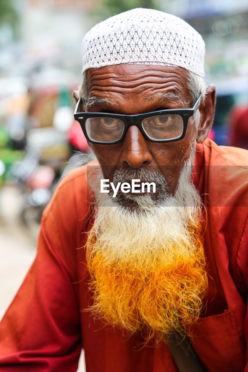 Portrait of senior man with dyed bear wearing eyeglasses