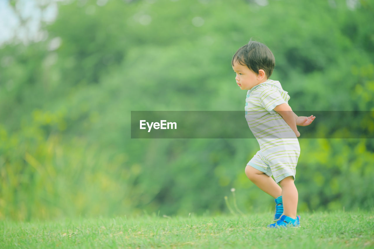 FULL LENGTH OF CUTE BOY PLAYING IN FIELD