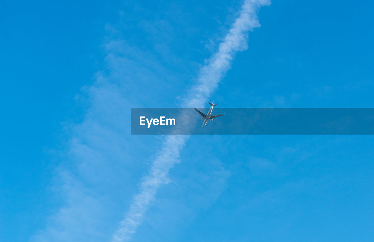 Low angle view of airplane flying against blue sky