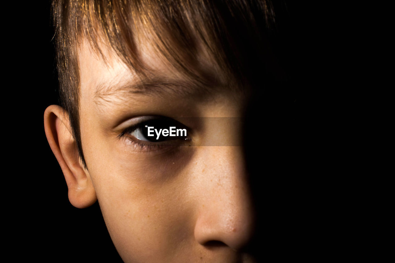 Close-up portrait of boy against black background