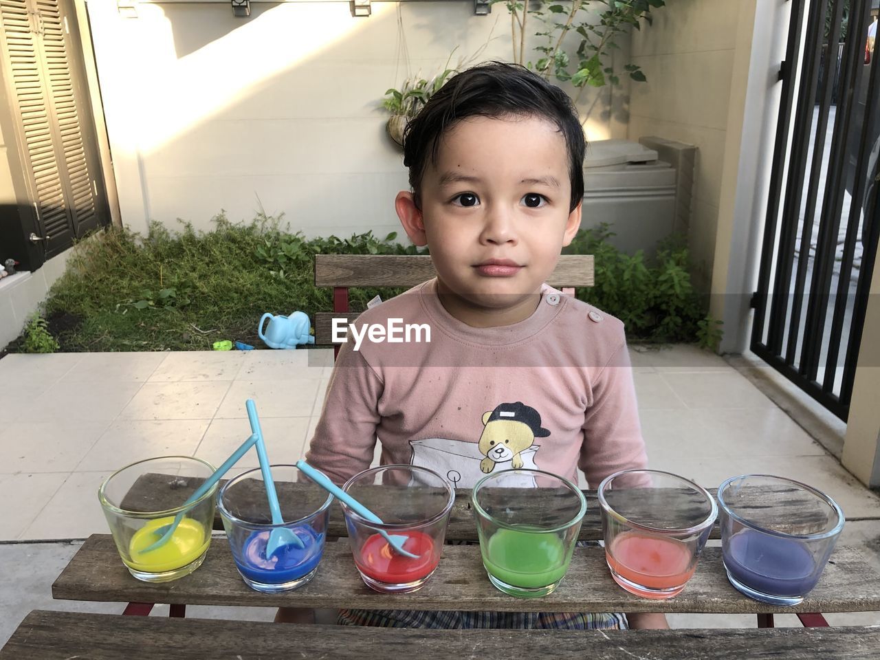 Cute boy with multi colored paints in glass on table
