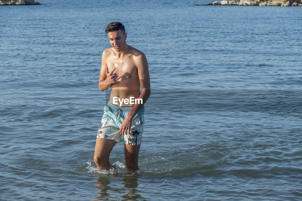 Shirtless man standing in sea