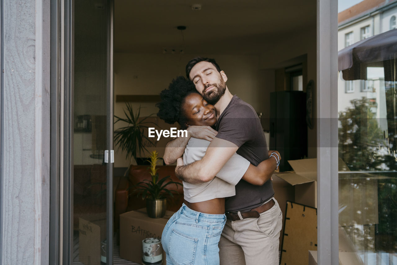 Romantic couple embracing each other with eyes closed at new home