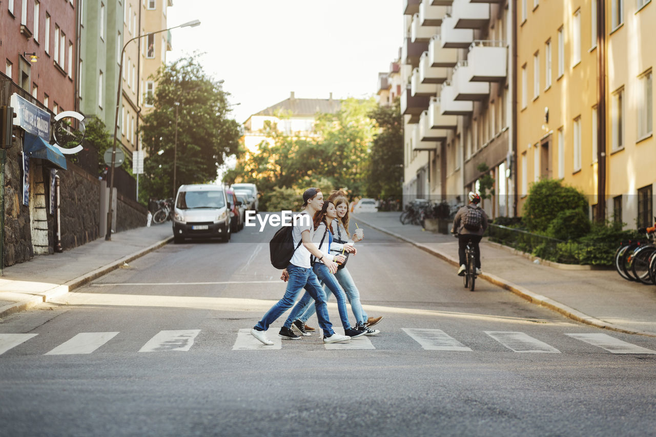 Side view of teenagers crossing road in city
