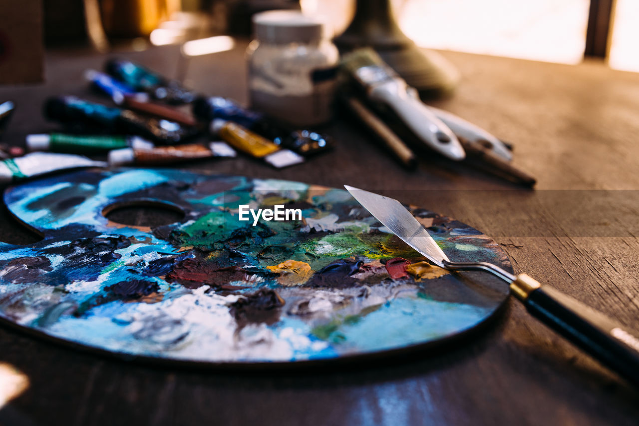 Palette in paint and a palette knife on a wooden table.