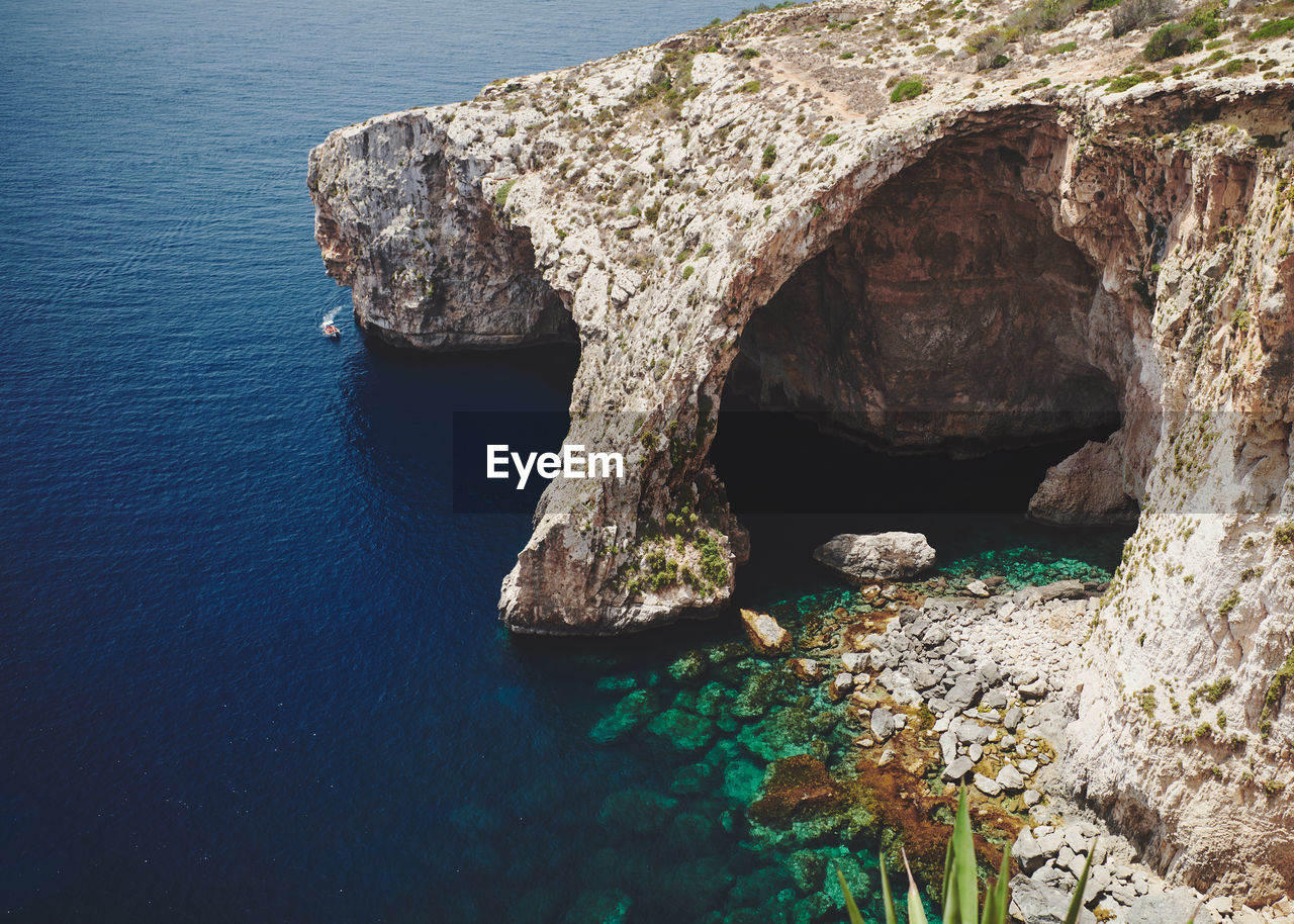 High angle view of rocks in sea at the blue grotto on malta