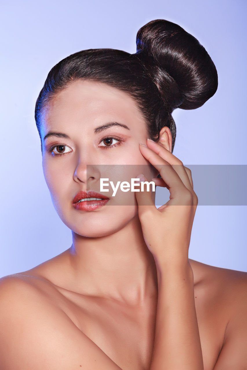 Close-up of shirtless beautiful woman against purple background