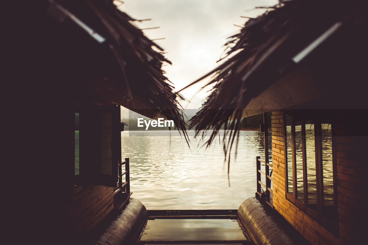 Stilt houses over river against sky