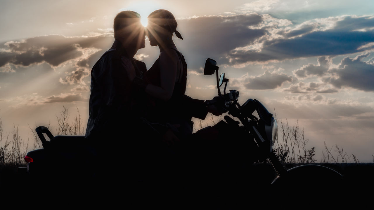 Silhouette couple on motorcycle against sky during sunset