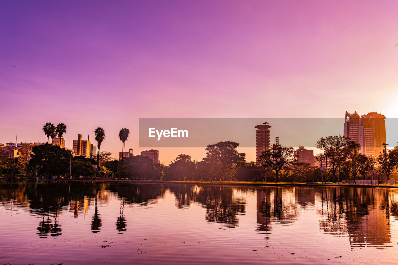reflection, dusk, sky, water, evening, sunset, architecture, skyline, city, landscape, nature, built structure, building exterior, cityscape, horizon, tree, building, twilight, urban skyline, lake, travel destinations, environment, beauty in nature, plant, sun, tranquility, outdoors, no people, travel, cloud, skyscraper, afterglow, scenics - nature, office building exterior, pink, business finance and industry