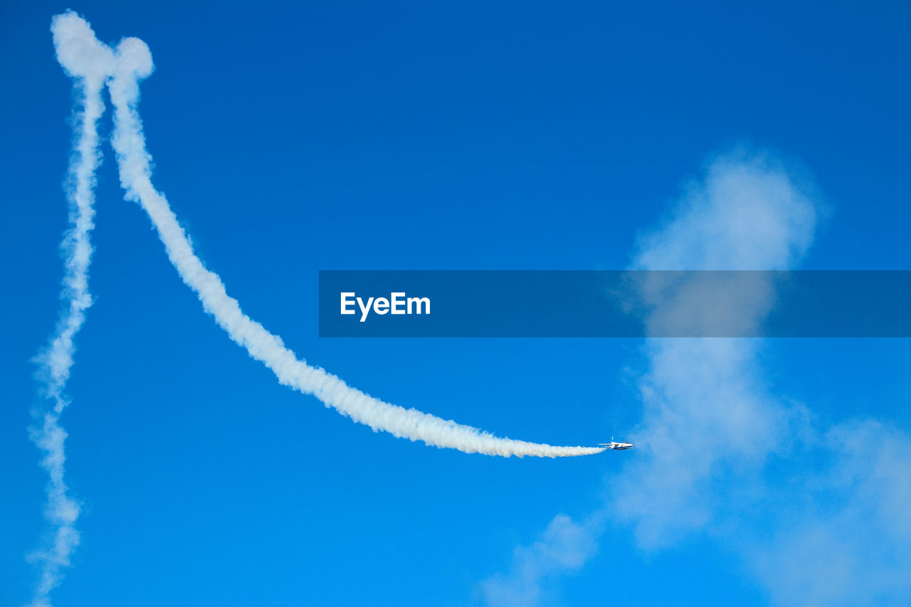 Low angle view of airplane with trails in flight