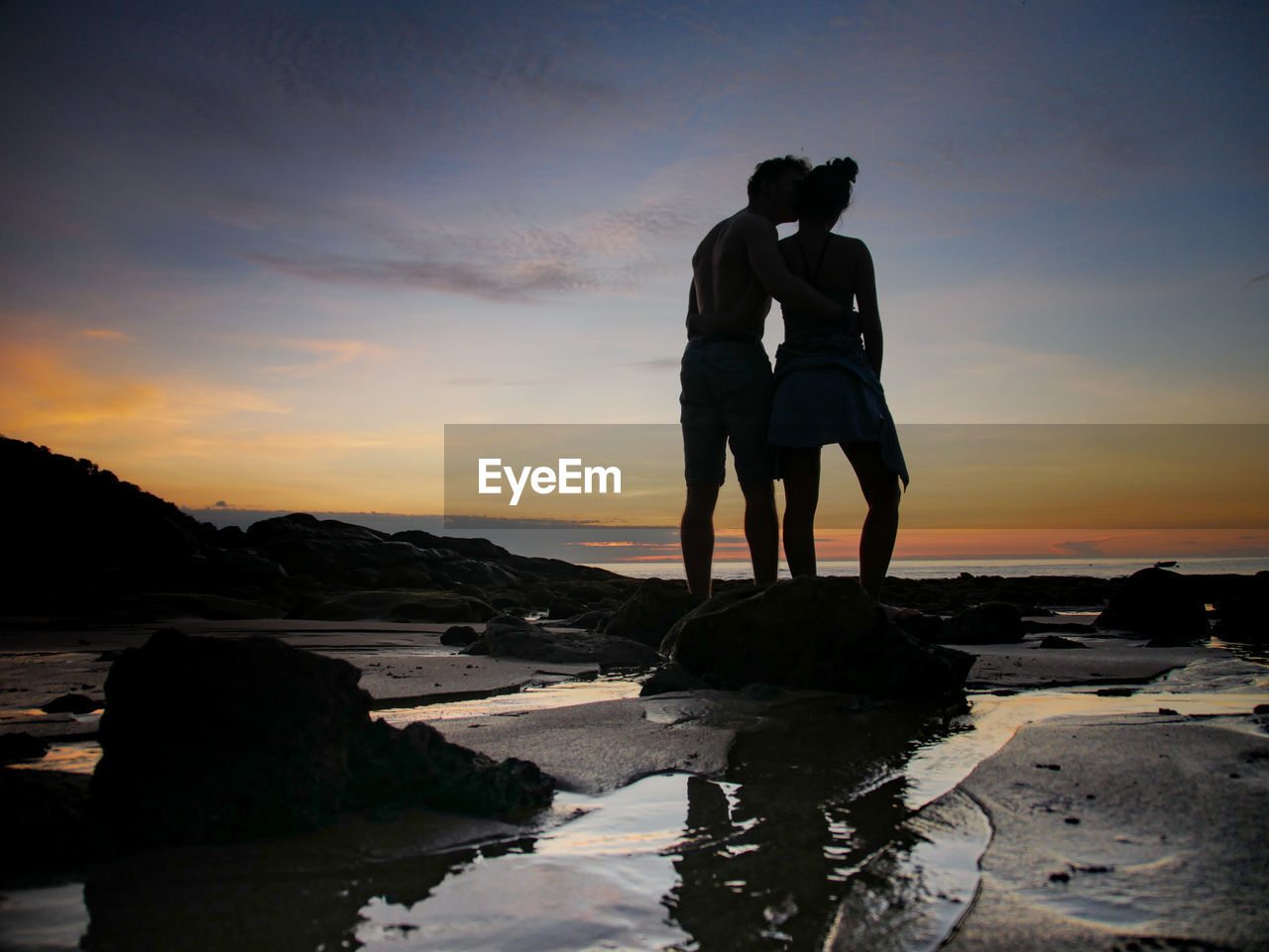 Silhouette couple at beach against sky during sunset