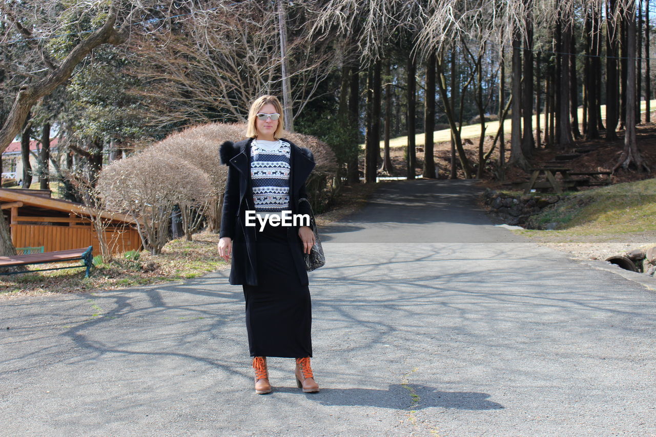 Full length of woman standing on road during sunny day