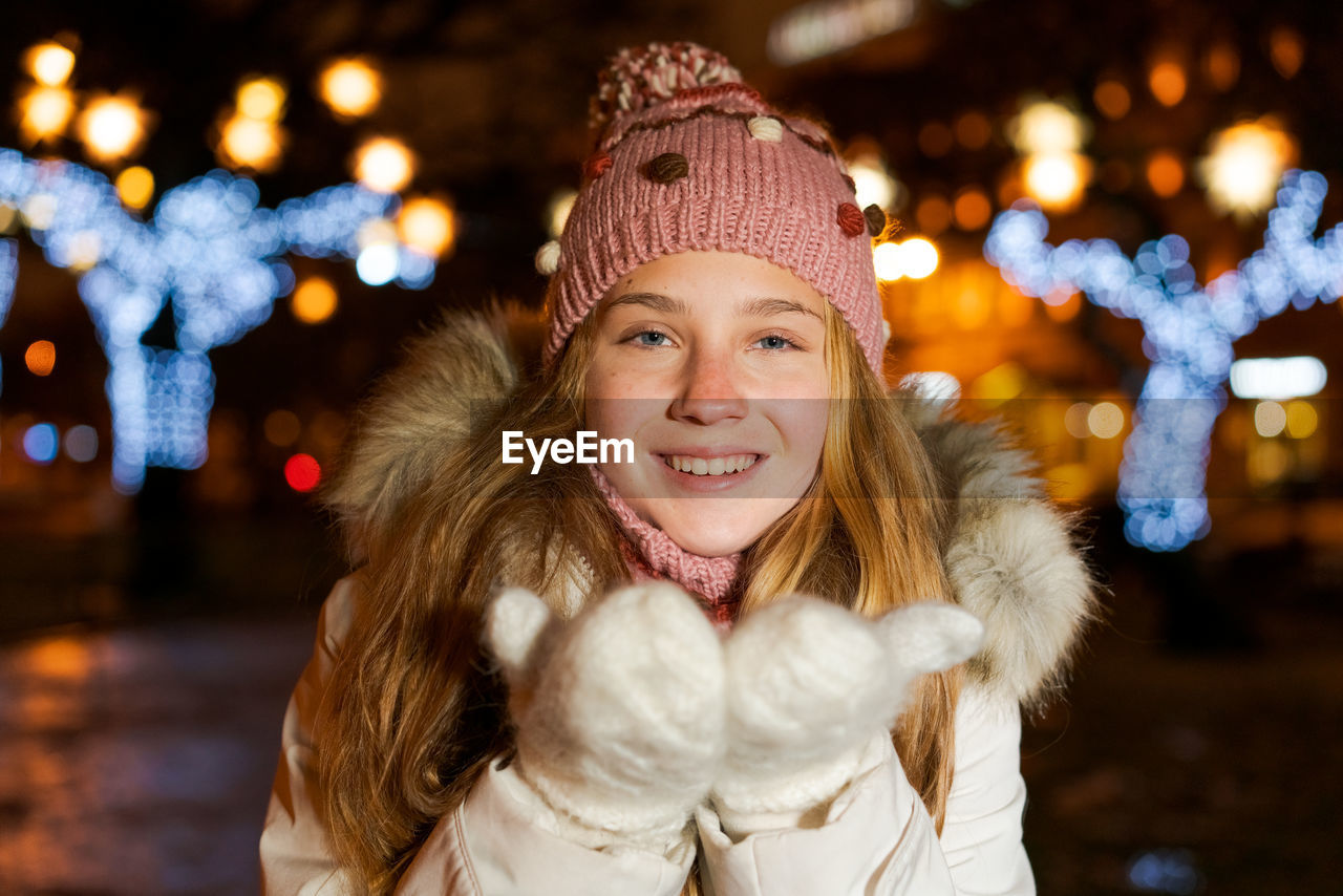 Portrait teenage girl on festive evening outdoors in winter holds her hands