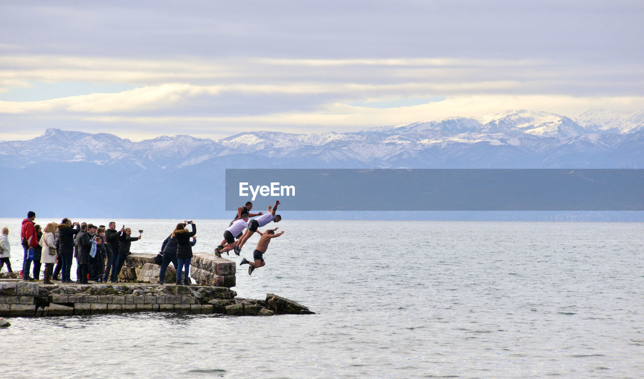 PEOPLE ON SHORE AGAINST MOUNTAINS