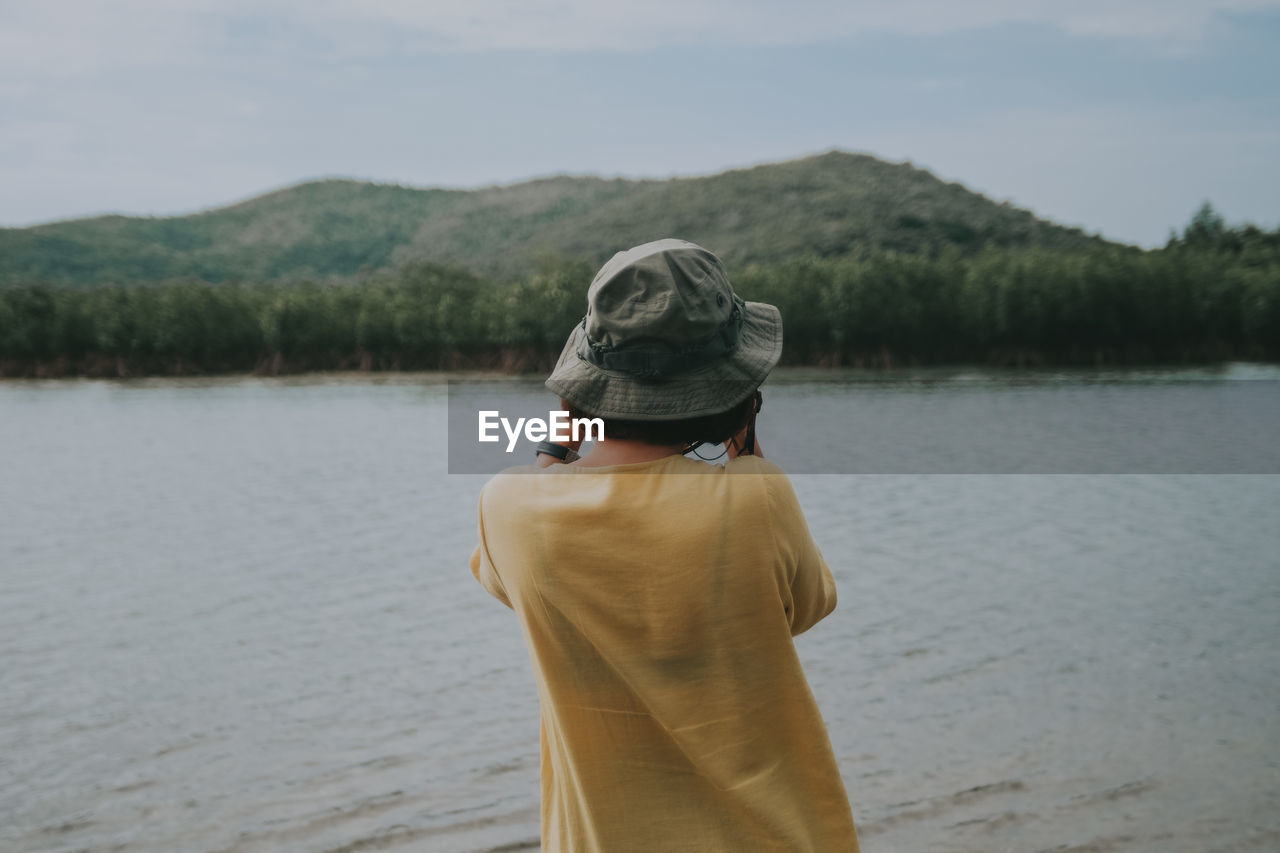 Rear view of woman looking at lake against sky