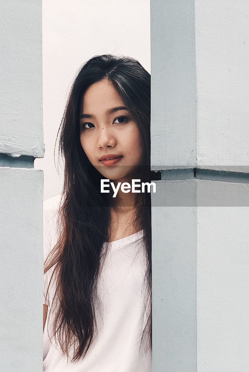 Portrait of beautiful young woman amidst columns