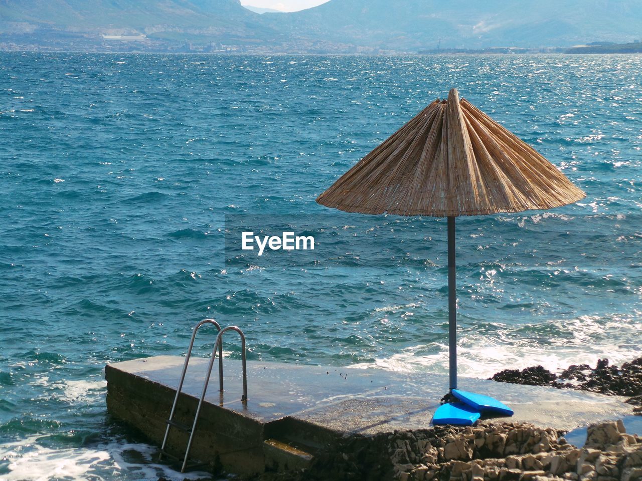 Parasol at jetty against mountains