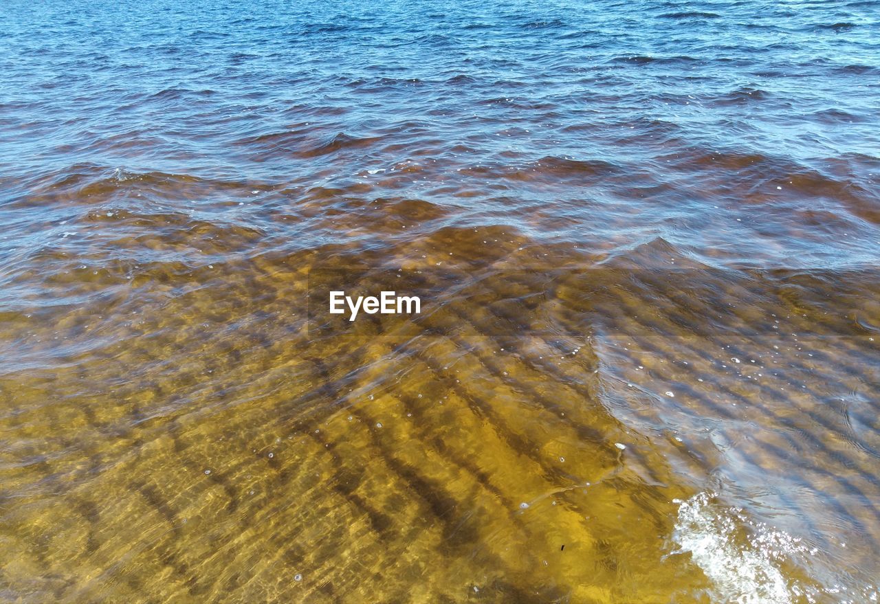 HIGH ANGLE VIEW OF WAVES BREAKING ON SEA