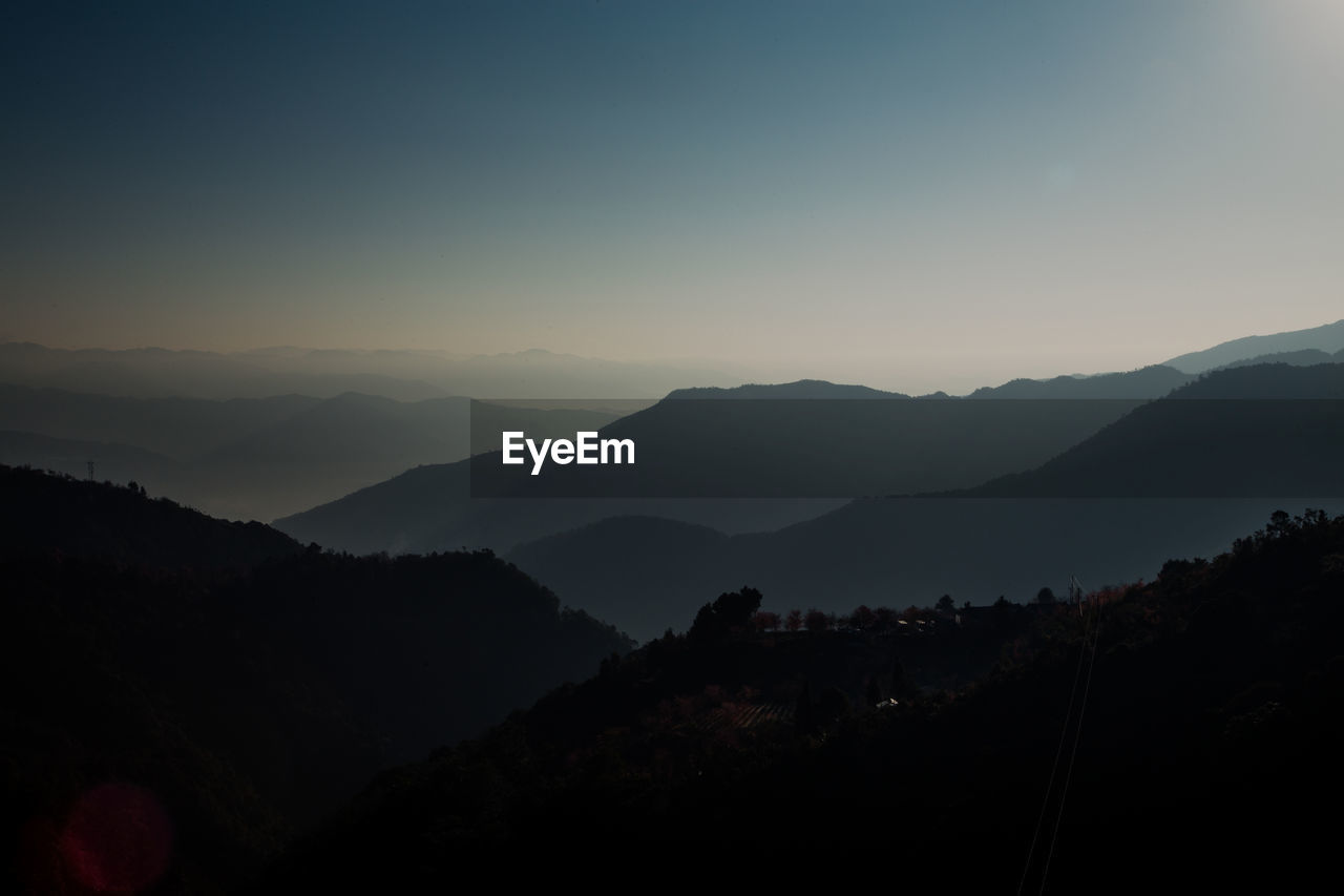 SCENIC VIEW OF SILHOUETTE MOUNTAINS AGAINST CLEAR SKY DURING SUNSET