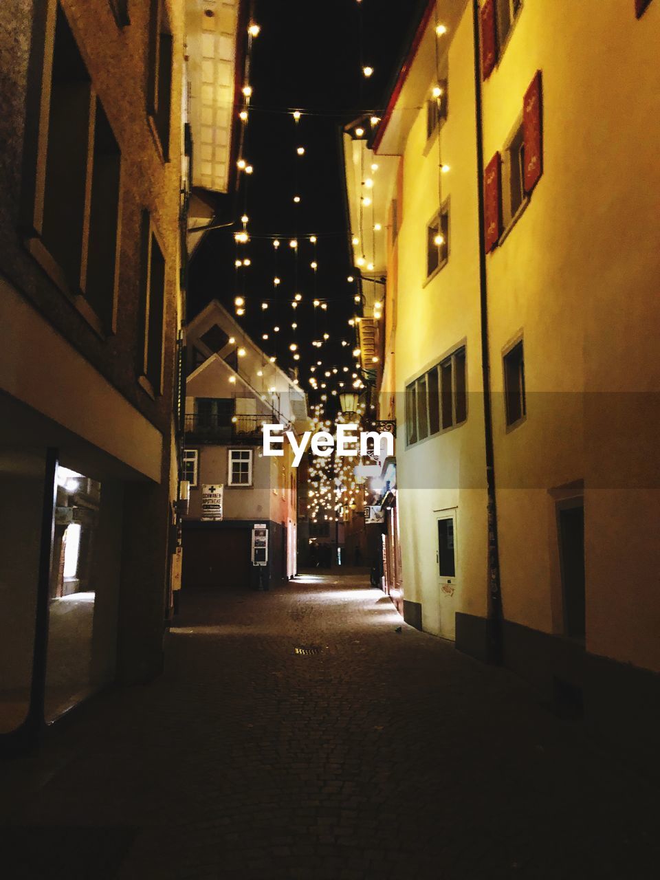 Illuminated street amidst buildings at night